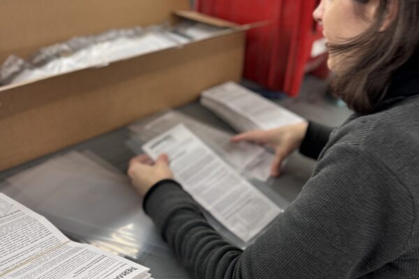 Nicky prepares instructions for Reeb Millwork hardware packages and prepares to heat seal them.